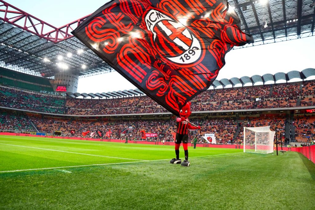 Mascotte Milanello con bandiera rossonera sul campo di San Siro durante una partita del Milan