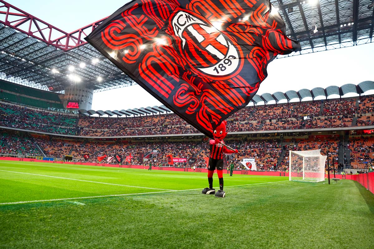 Mascotte Milanello con bandiera rossonera sul campo di San Siro durante una partita del Milan