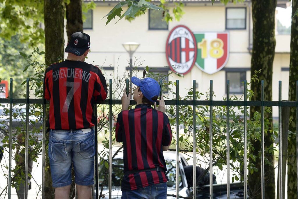 Tifosi del Milan, papà e figlio con maglia di Shevchenko, osservano Milanello da dietro la cancellata