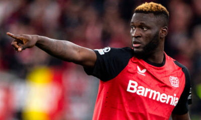 Victor Boniface con il braccio teso indica qualcosa ai compagni di squadra del Bayer Leverkusen durante una partita