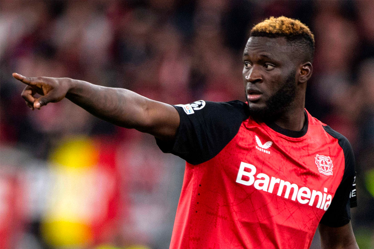 Victor Boniface con il braccio teso indica qualcosa ai compagni di squadra del Bayer Leverkusen durante una partita