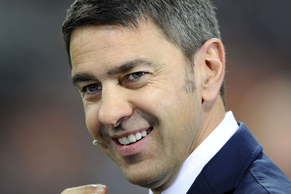 Alessandro Costacurta in giacca e cravatta commenta una partita a bordocampo come opinionista